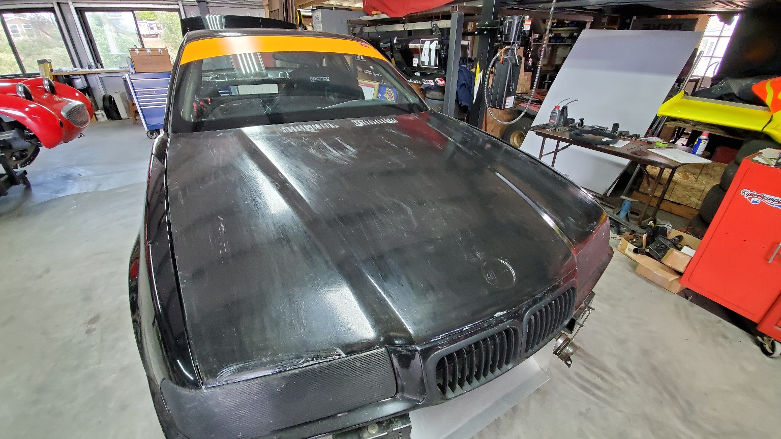 Carbon-fiber hood installed on the number 42 E36 BMW in the workshop