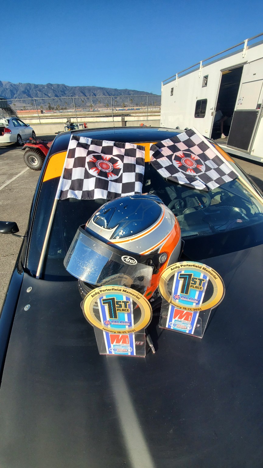 Helmet, checkered flags, and first-place awards displayed on the E36 BMW