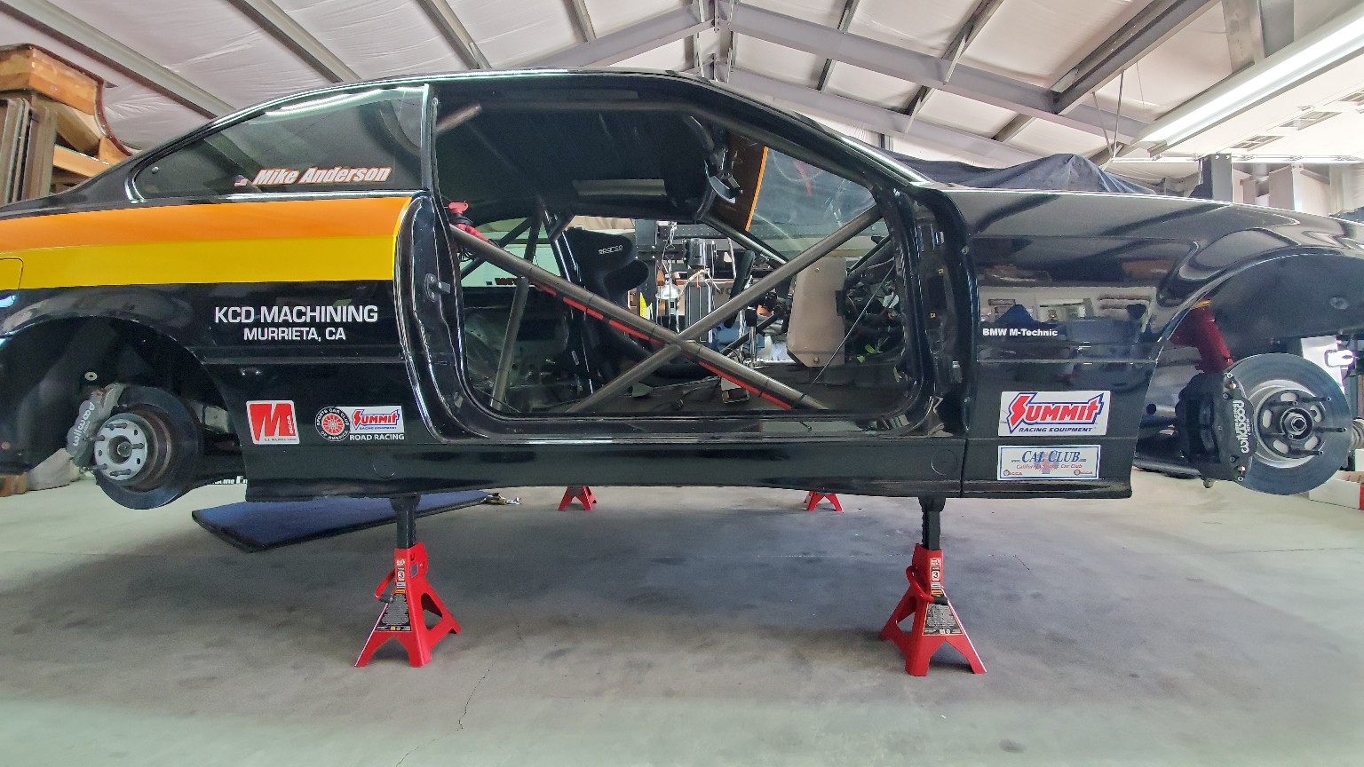 E36 BMW on stands with the door removed for chassis and systems work