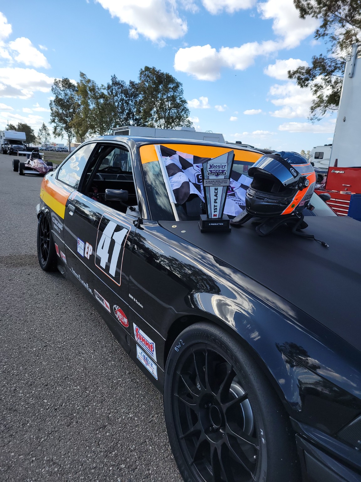 Side view of the E36 BMW race car with awards displayed on the hood