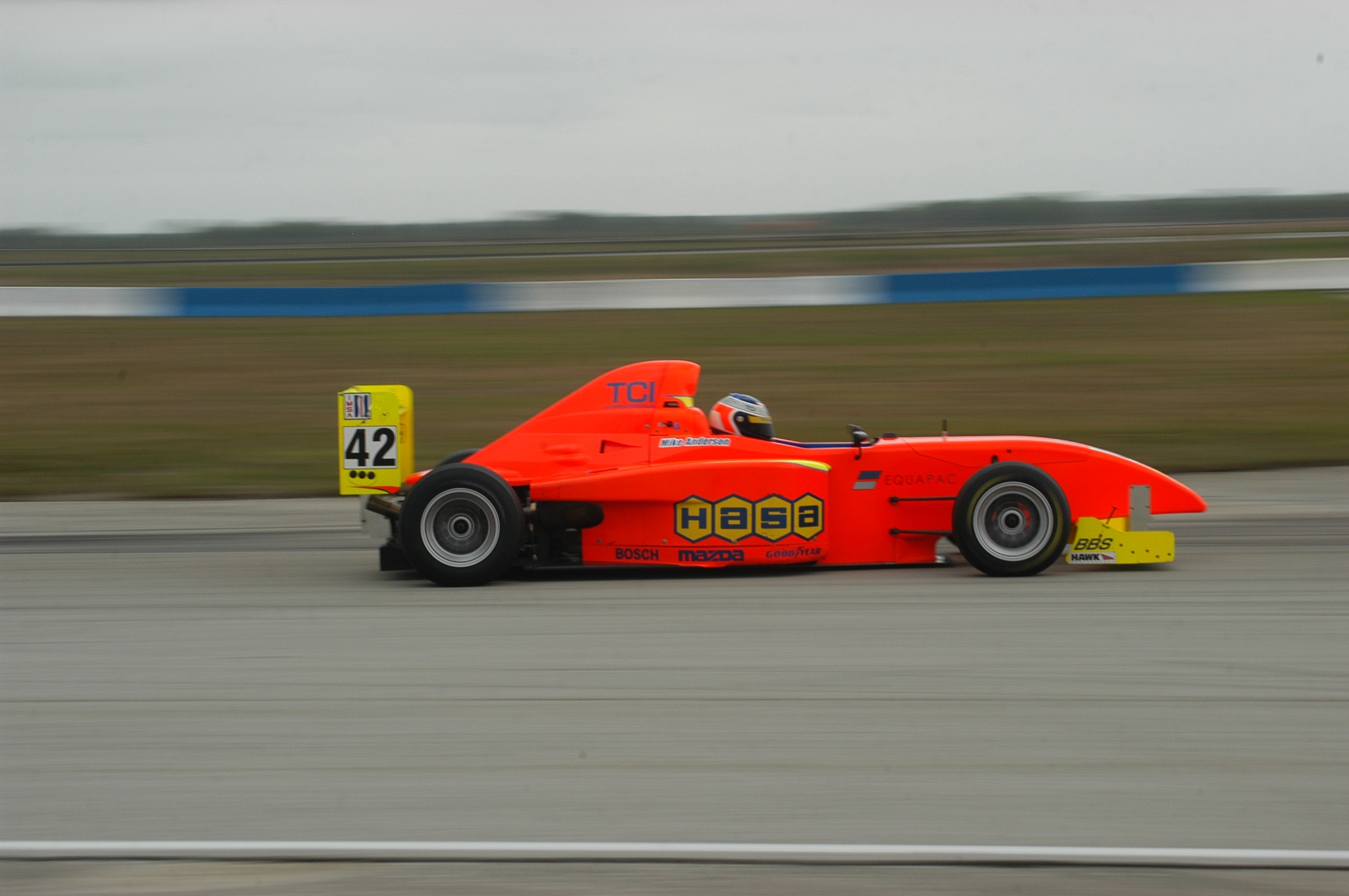 Mike Anderson driving the orange and yellow number 42 Pro Formula Mazda at speed