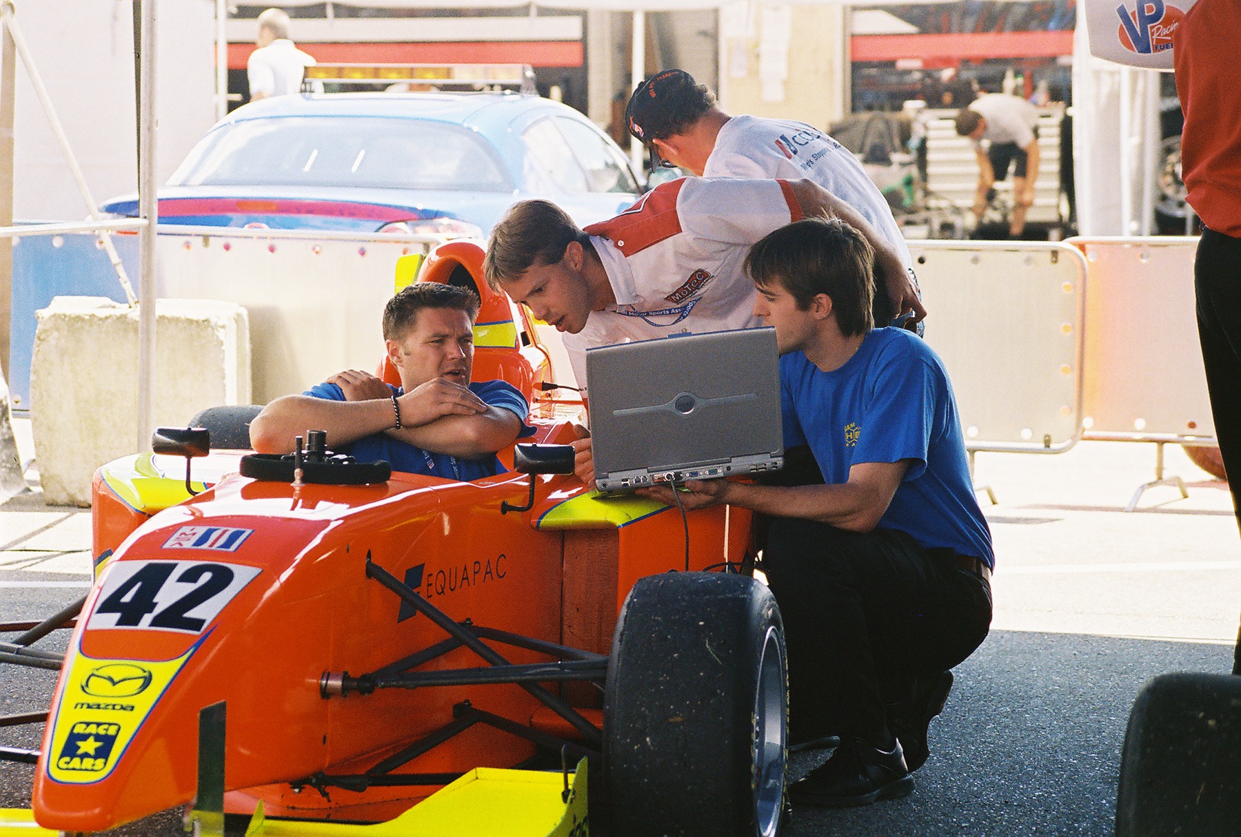 Mike Anderson and crew reviewing data on a laptop beside the number 42 Pro Formula Mazda